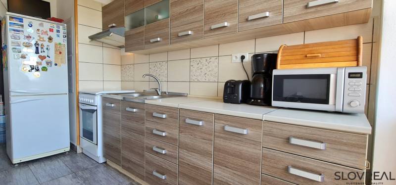 A kitchen in a 2-room apartment with a wooden decor floor and appliances.