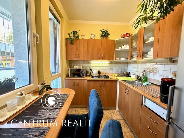 A kitchen in a studio apartment with wooden cabinets and a dining table.