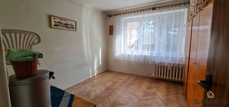 A room with a window and a wooden decor floor in a 3-room apartment.