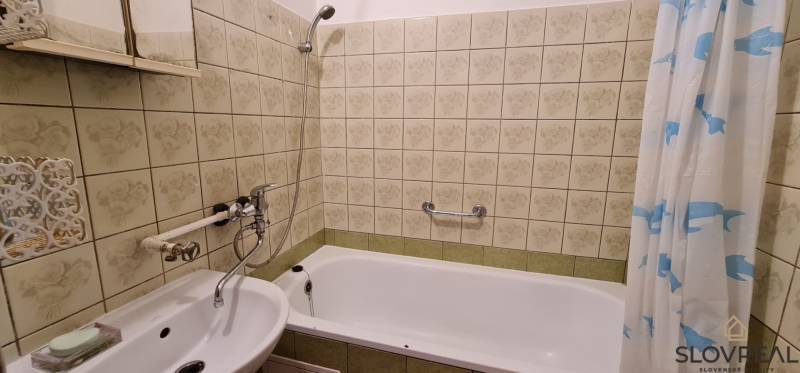 Bathroom with a mirror and a bathtub in a 3-room apartment, decorated with decorative tiles.