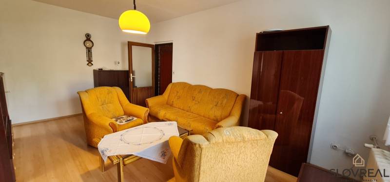 A living room in a three-room apartment with brown furniture and yellow sofas.
