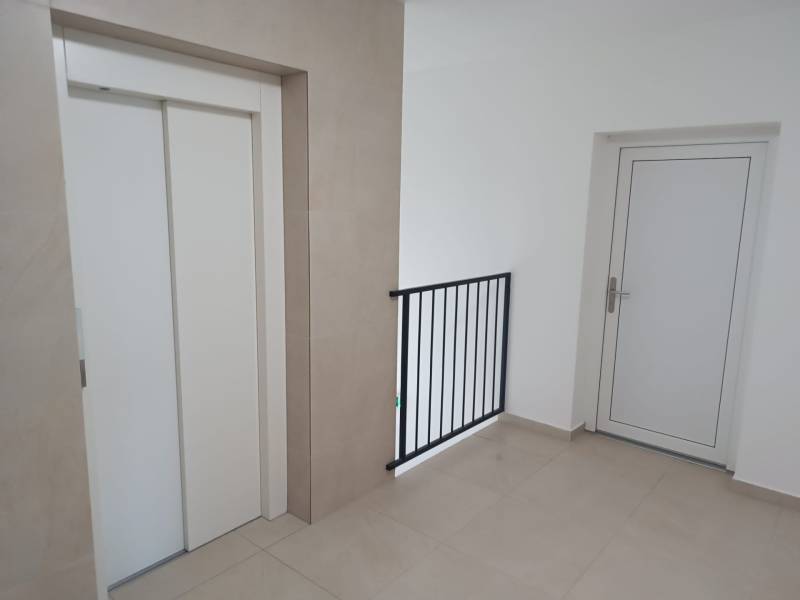 Hallway with an elevator and white doors in a 2-room apartment.