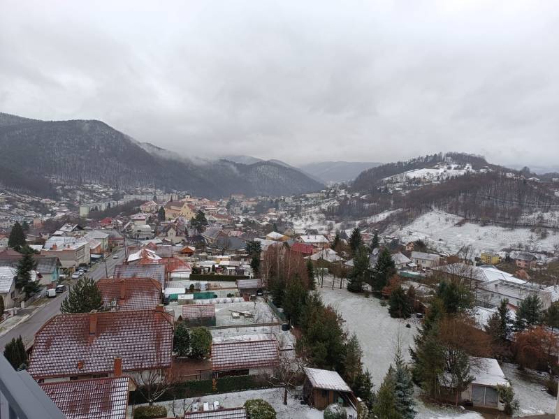 Winter panorama of Nová Baňa from Pod sekvojou street with snow-covered hills and roofs.