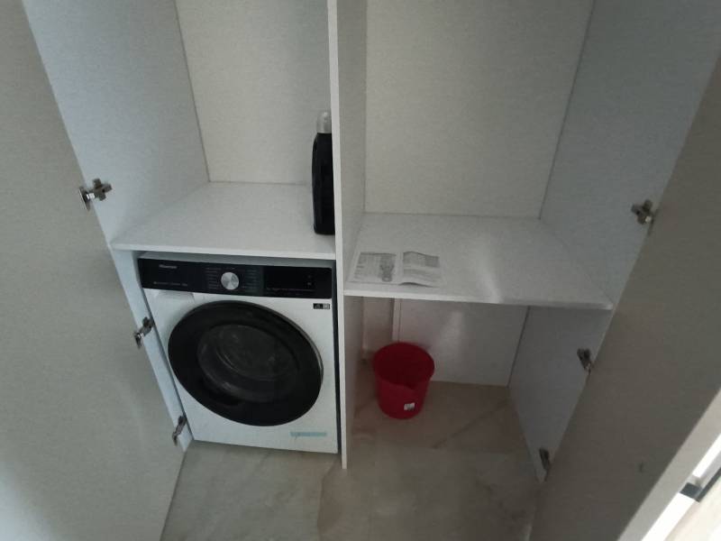 In the 2-room apartment, there is a washing machine in the storage space and a red bucket.