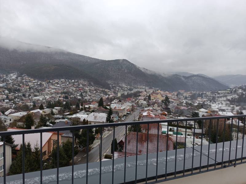 View of the snowy town of Nová Baňa from Pod sekvojou Street with a mountain panorama.