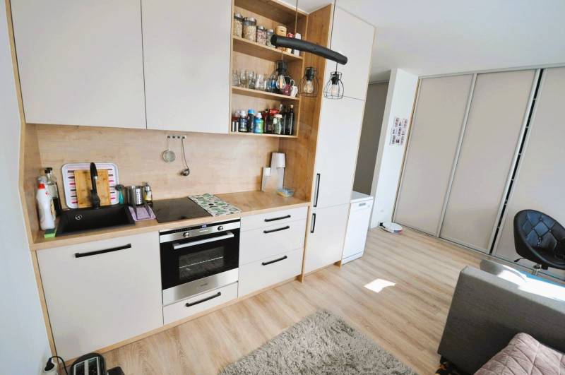 A small kitchen unit in a studio apartment with a wooden decor floor.