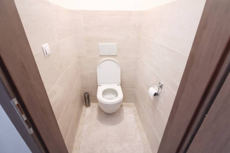 A toilet in a 2-room apartment with white ceramics and beige tiles on the walls.