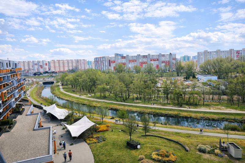 View from a 2-room apartment of greenery, a water stream, and panel buildings in Bratislava - Petržalka.