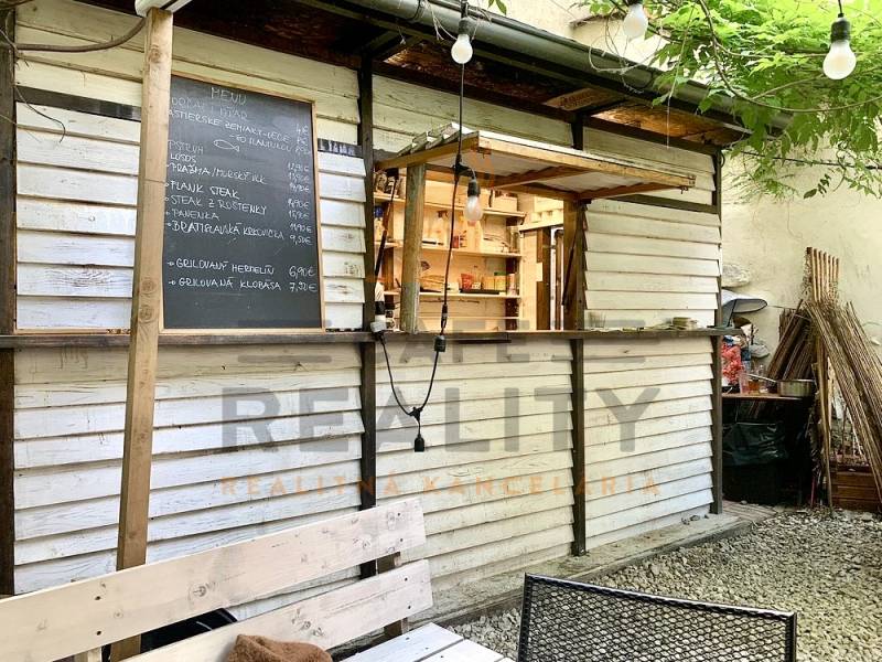 Exterior of a gastro space on Sedlárska Street in Bratislava with a menu and wooden seating.