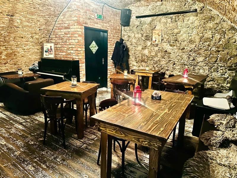 Gastro premises with stone walls, a piano, and a floor with a wooden decor.