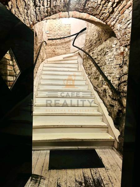 Stone stairs leading upwards in historical gastro premises with a wooden decor floor.