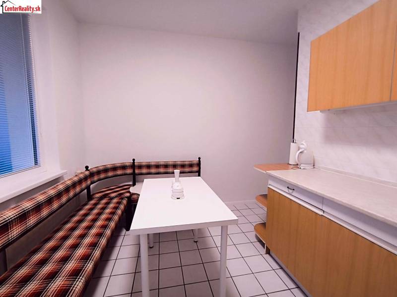 A kitchen in a 2-room apartment with seating and white tiles on the floor.