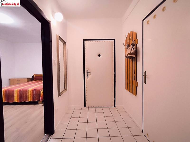Hallway in a 2-room apartment with white walls, tiles, and a mirror.