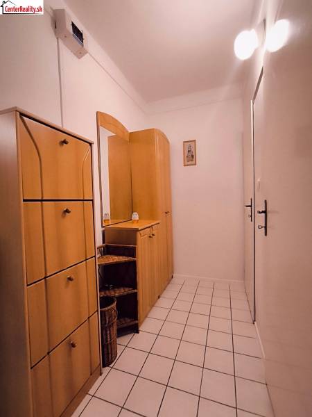 A hallway in a 2-room apartment with tiles and wooden furniture.
