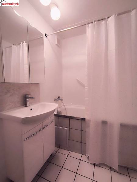 Bathroom in a 2-room apartment with a sink, mirror, bathtub, and white tiles.