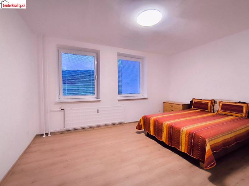 Bedroom with a colorful bed and wooden decor flooring in a two-room apartment.