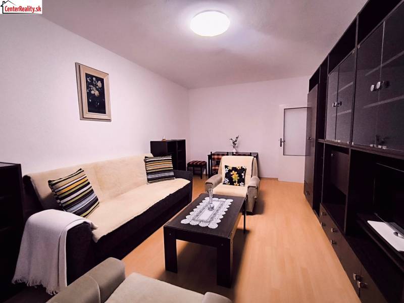 Living room with a sofa, decorative pillows, and a wooden decor floor in a two-room apartment.