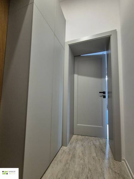 A narrow corridor with white cabinets and a wooden decor floor in a studio apartment.