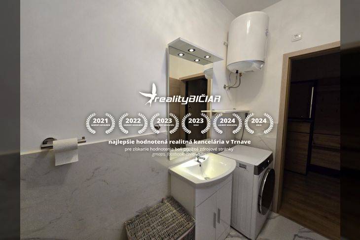 Bathroom of a holiday apartment with a washing machine, sink, and gas water heater.