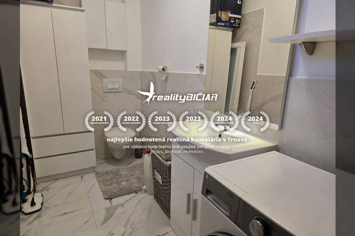 A bathroom in a holiday apartment with a washing machine and marble wall decor.
