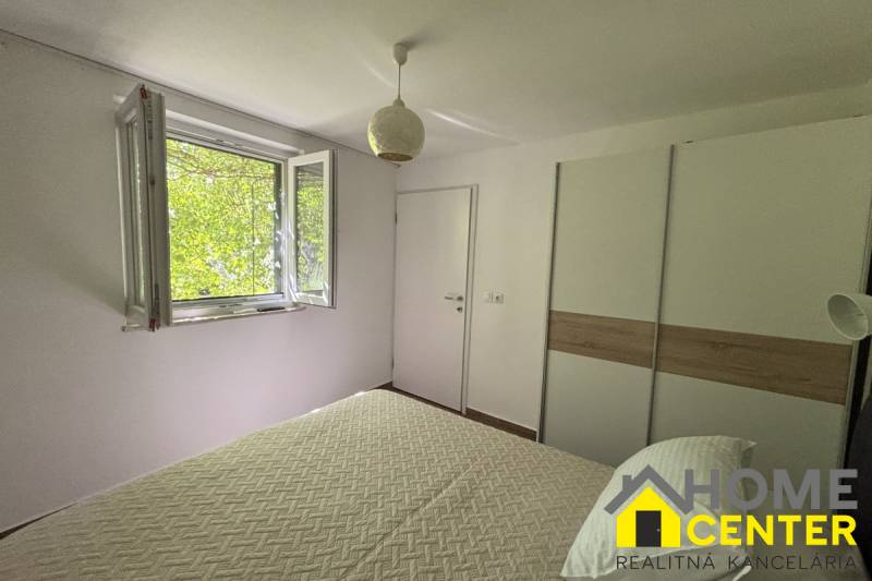 Bright bedroom with a window, white wall, and wardrobe in a family house.