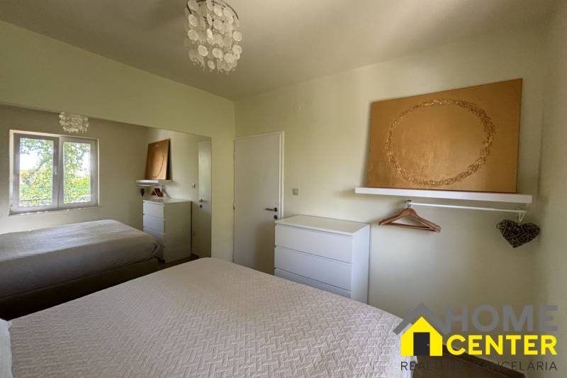 A bedroom in a family house with white furniture, a mirror, and textured bed covers.