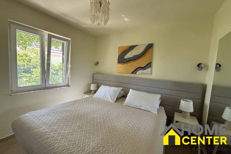 Bedroom in a family house with a double bed, tables with lamps, large window.