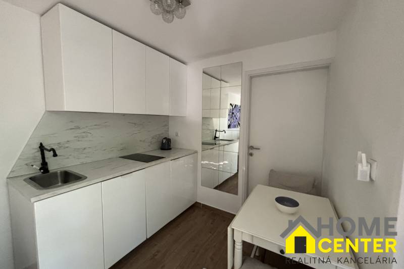 The kitchen area of a family house with white cabinets and a wooden decor floor.