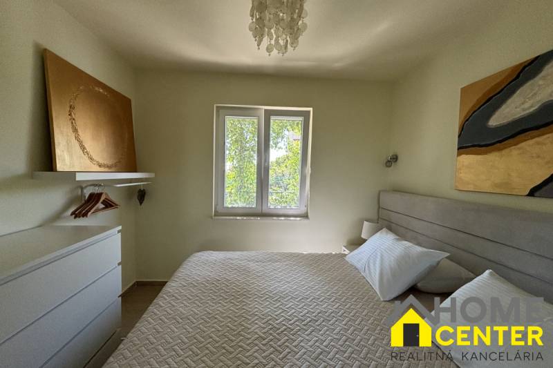 A bedroom in a family house with art on the walls and a pendant light.