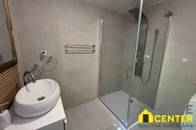 Bathroom in a family house with a sink, shower, and towel racks.
