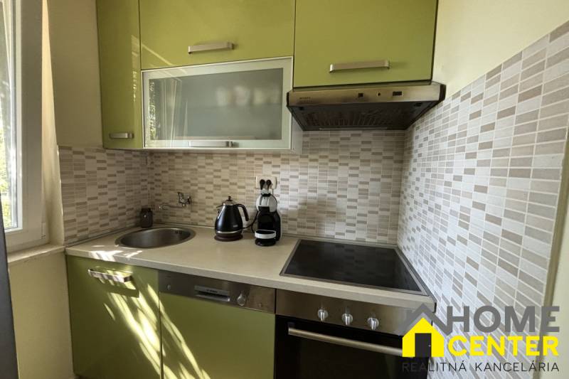 A kitchen in a family house with green cabinets, tiles, and built-in appliances.