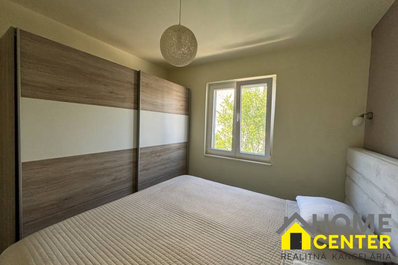 A bedroom in a family house with a French window and a large wardrobe.