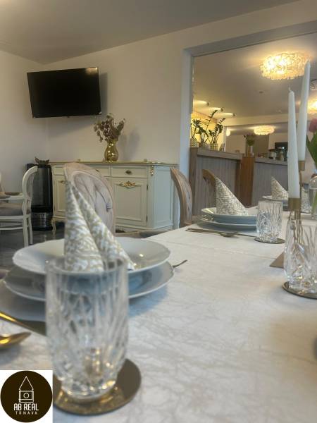 Set tables in a dining area with a television, golden decorations, and elegant table settings.
