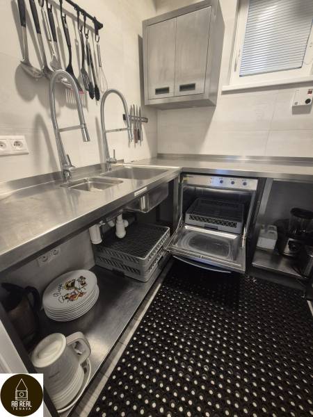 A kitchen in a gastro space with stainless steel sinks, appliances, and organized kitchen tools.