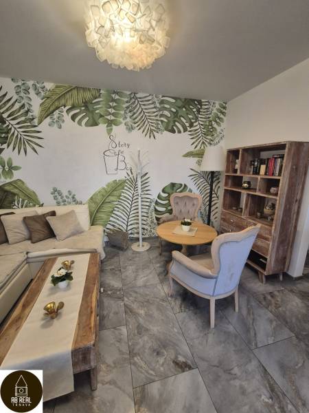 Interior of gastro spaces with plant wallpaper, comfortable furniture, and wooden decor.