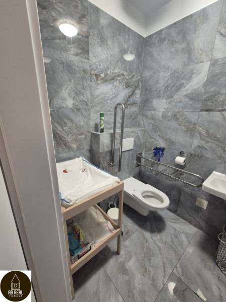 Gray bathroom tiles, changing table, and toilet in dining areas.