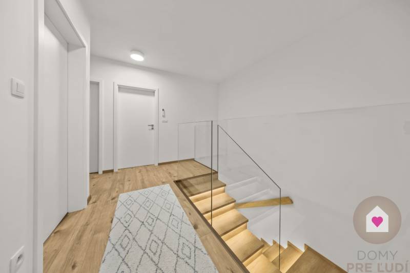 A hallway with a staircase featuring glass railings and a floor with a wooden decor in a 4-room apartment.