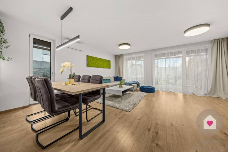Dining and living area in a 4-room apartment with wood-patterned flooring.
