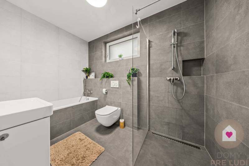 Bathroom in a 4-room apartment with a bathtub, shower, and toilet, gray tiles.