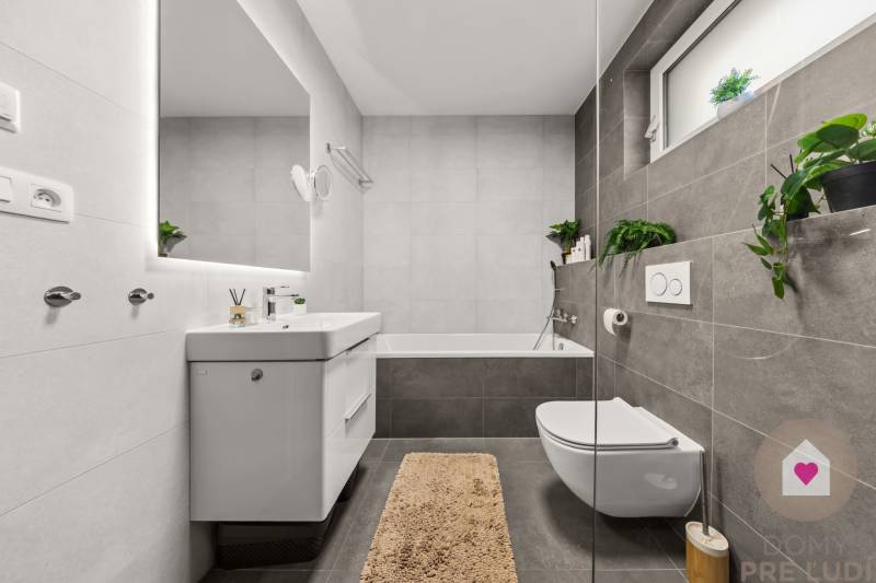 Bathroom in a 4-room apartment with a bathtub, white sink, and plants.
