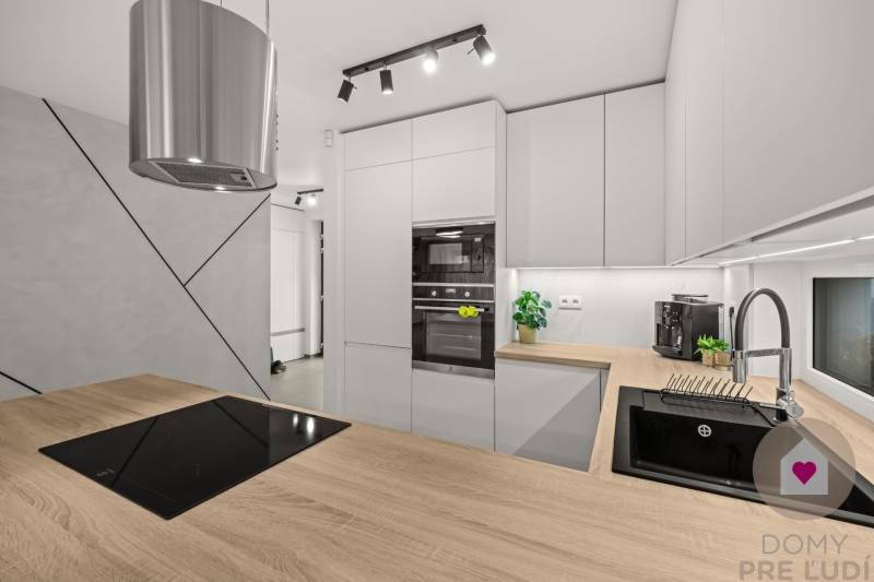 A kitchen in a 4-room apartment, with a wooden decor floor and modern kitchen equipment.