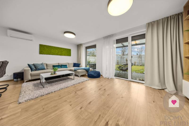 Living room with a sofa, glass doors, and a wooden decor floor in a 4-room apartment.