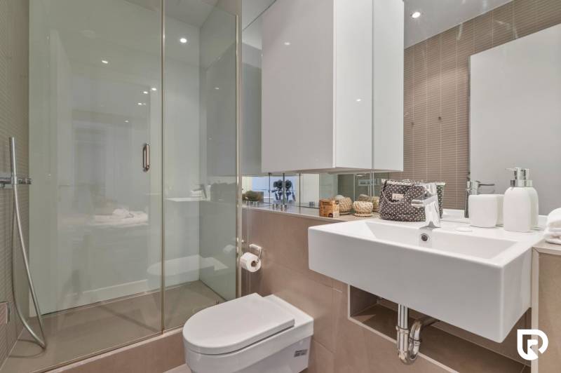 Bathroom in a 2-room apartment with a toilet, sink, shower, and modern mirror.