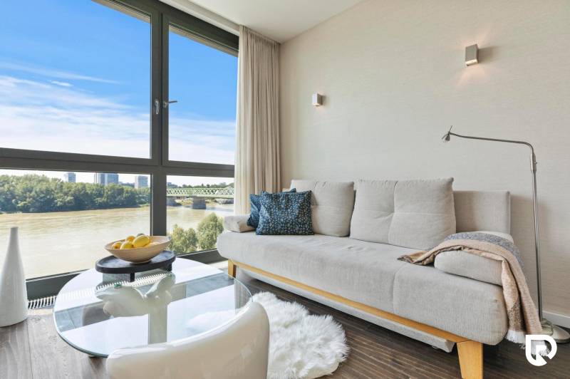 Living room in a two-room apartment with a sofa and a large window with a view.