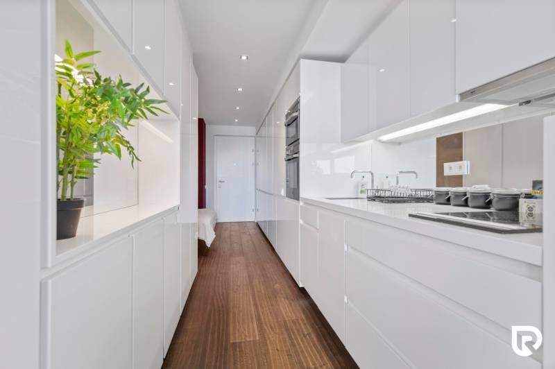 A kitchen in a 2-room apartment with white cabinets and a wood-patterned floor.