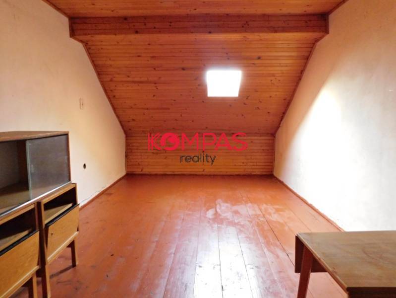 Attic space with a sloped ceiling and wooden floor, suitable for commercial premises.
