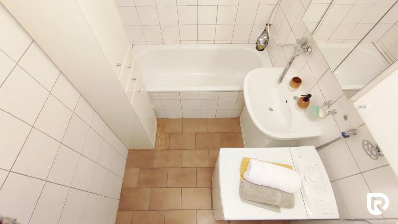 Bathroom in a 2-room apartment with a bathtub, sink, and washing machine.