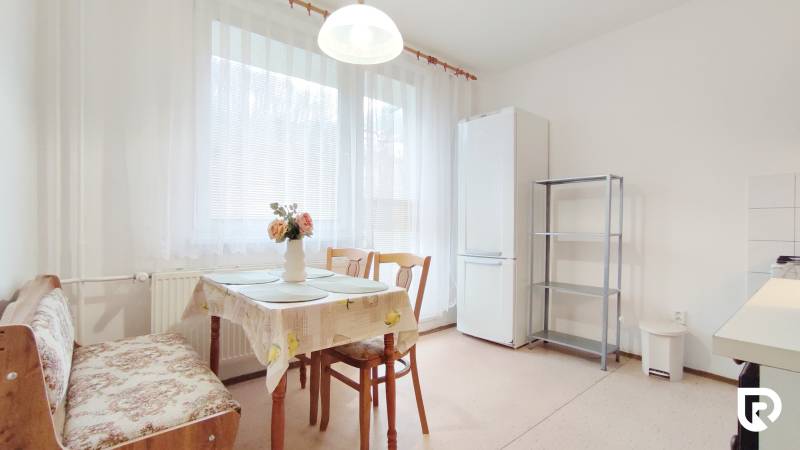 Kitchen in a 2-room apartment with a dining table, chairs, and a refrigerator.