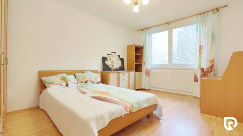 A bedroom in a 2-room apartment with a bed, furniture, and a wooden decor floor.