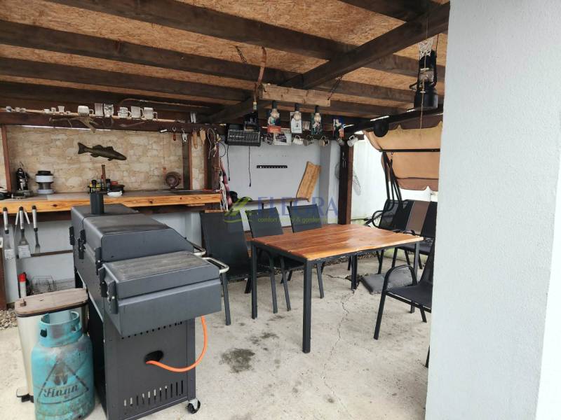 Covered seating area in a family house in Tornyosnémeti with a grill and a table.